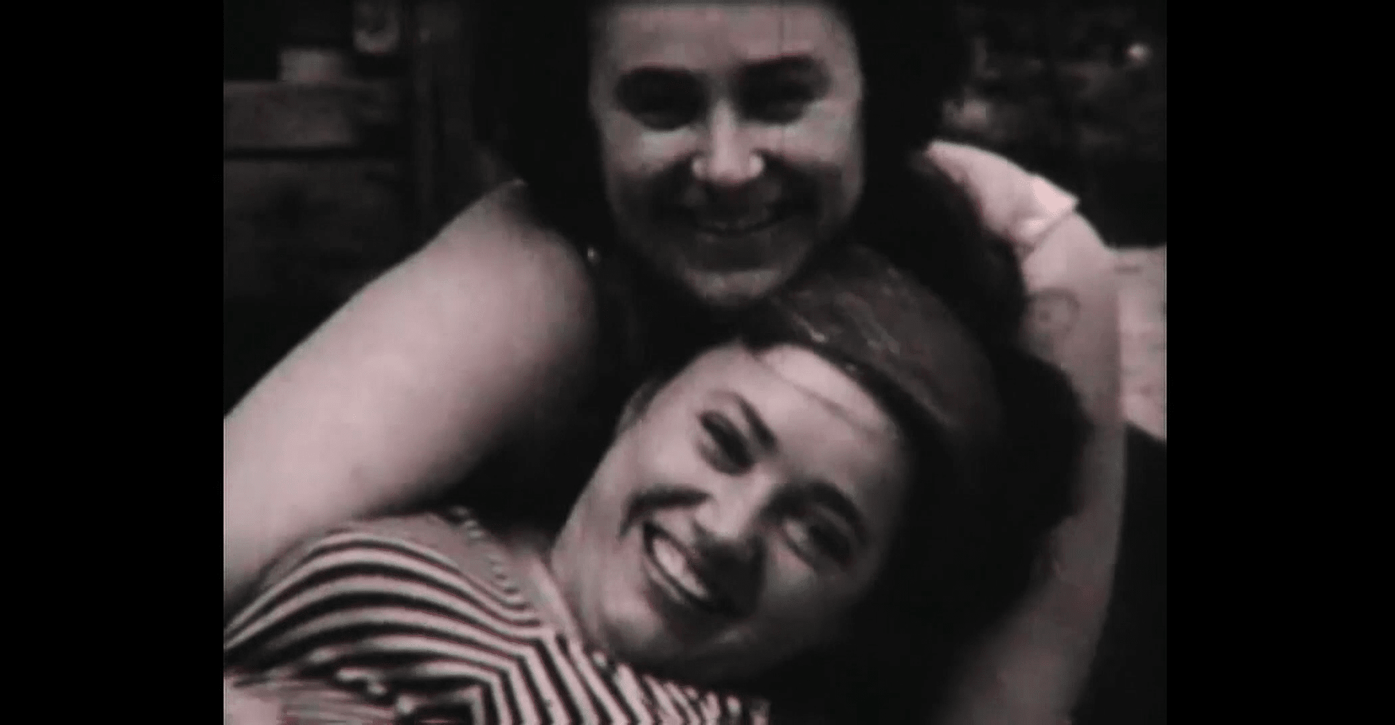 Still from the film "The Wonderful Years". Two-shot. Old black and white portrait of two smiling women, one hugging another. Both looking directly at the viewer.
