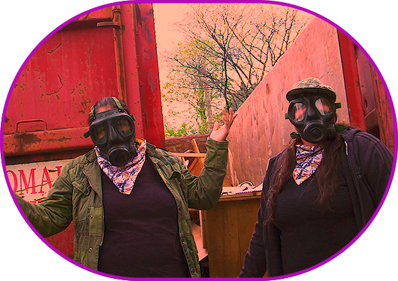 Still from the film "Reclamation". Two-shot. Toxic colors. Two people wearing gas masks are standing in front of the dumpster full of junk. One of them is gesticulating actively.
